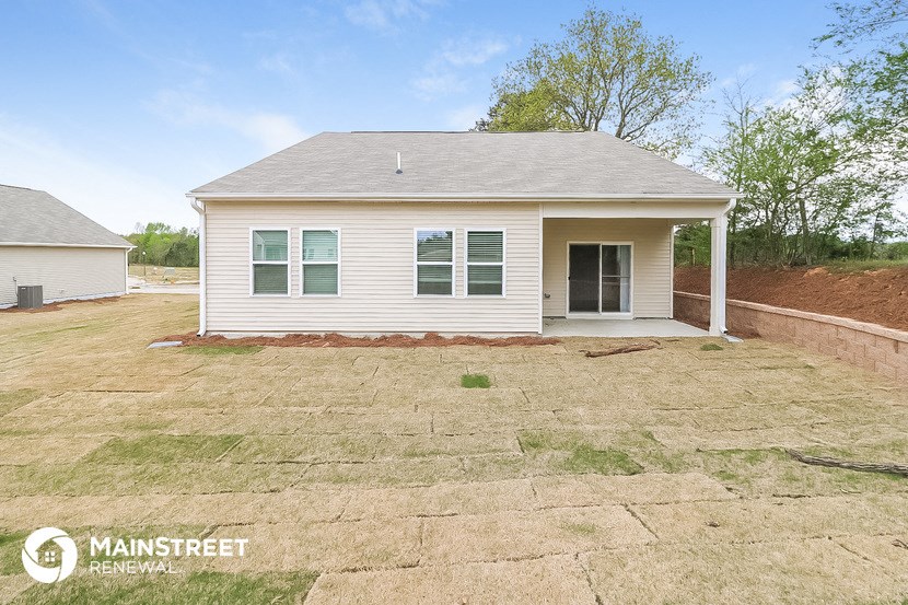 the front of a small white house with a yard and grass