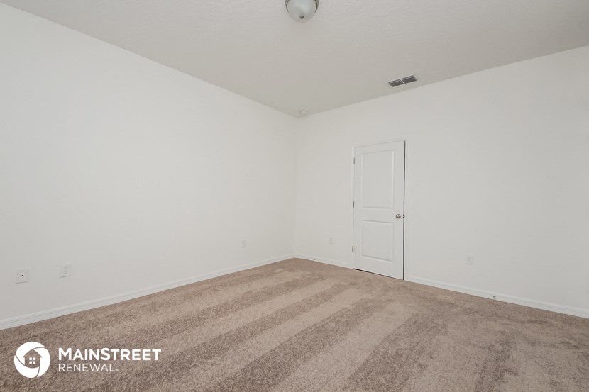 the living room of an apartment with white walls and carpet