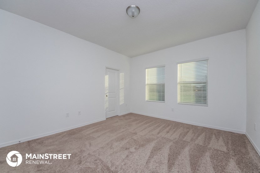 the spacious living room with carpeting and white walls