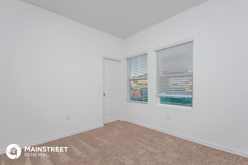 the living room of an apartment with white walls and carpet