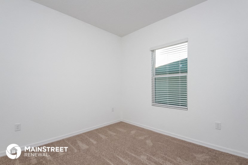 the spacious living room with carpeting and a window
