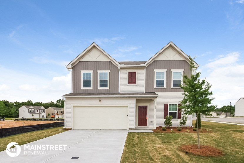 a beige and white house with a garage door and a lawn