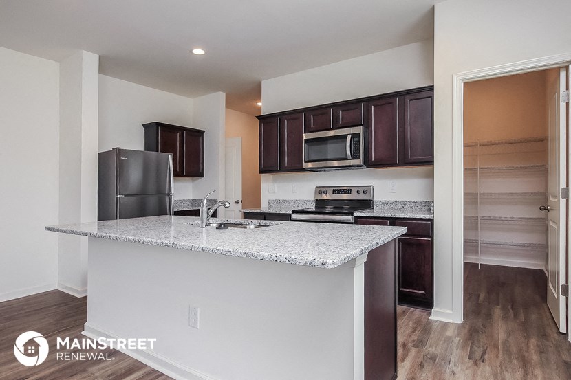 a kitchen with a marble counter top and a stainless steel refrigerator