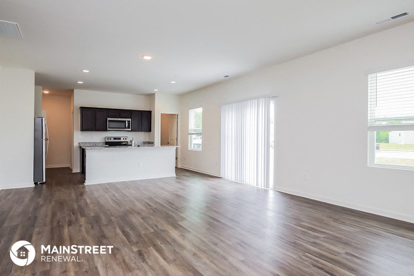 the living room and kitchen of an apartment with wood flooring