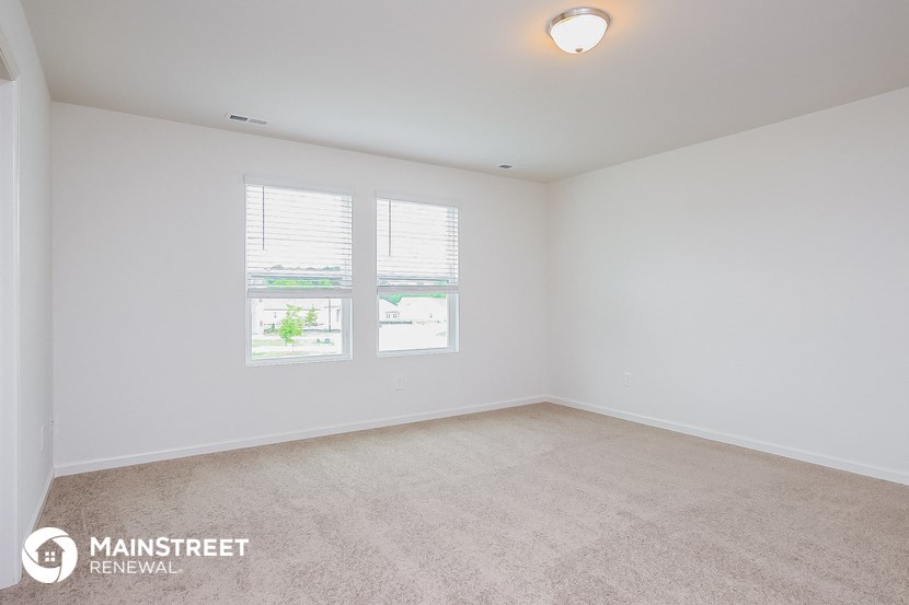 the spacious living room with carpeting and two windows