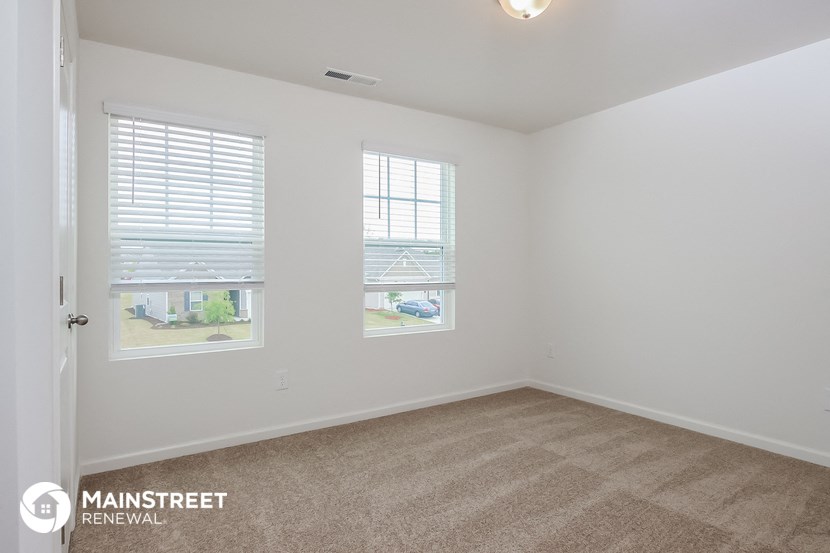a bedroom with a carpeted floor and three windows