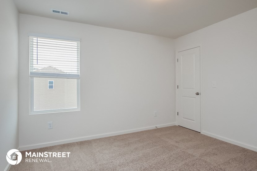 the bedroom of an apartment with carpet and a door