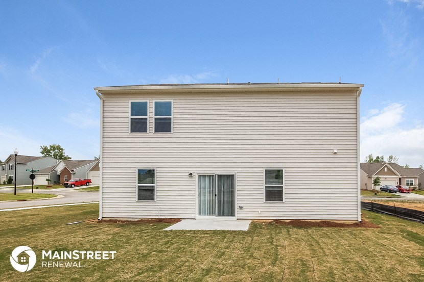 the exterior of a small white house with a garage and a yard