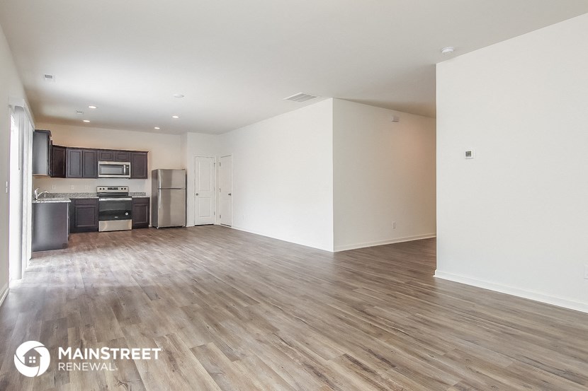 the living room and kitchen of an apartment with wood flooring