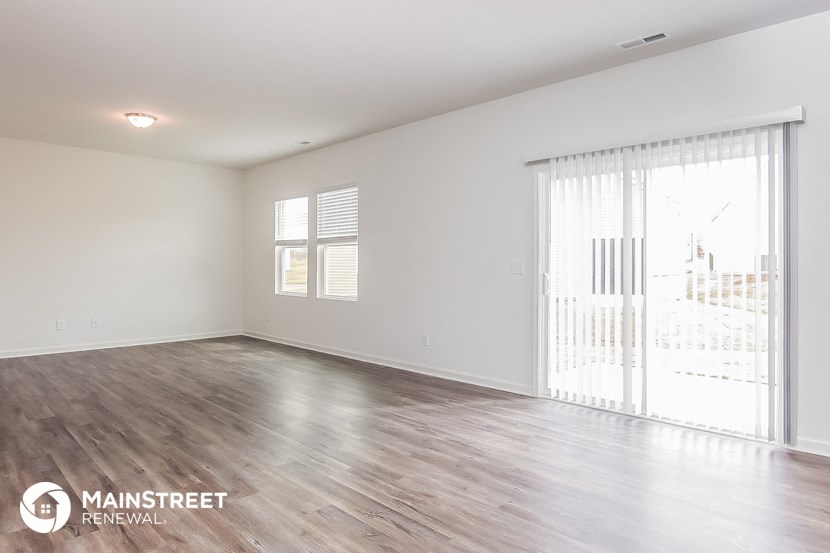the spacious living room with wood flooring and a large window