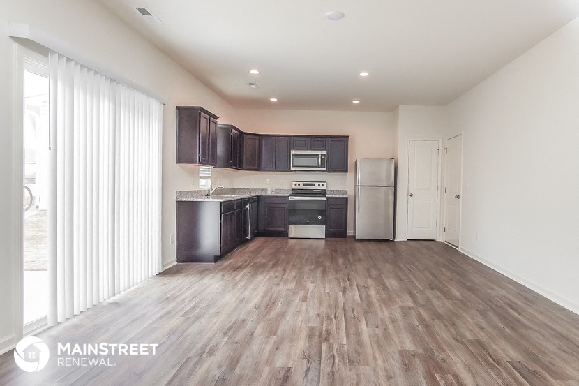 a spacious kitchen with wood flooring and black cabinets and stainless steel appliances