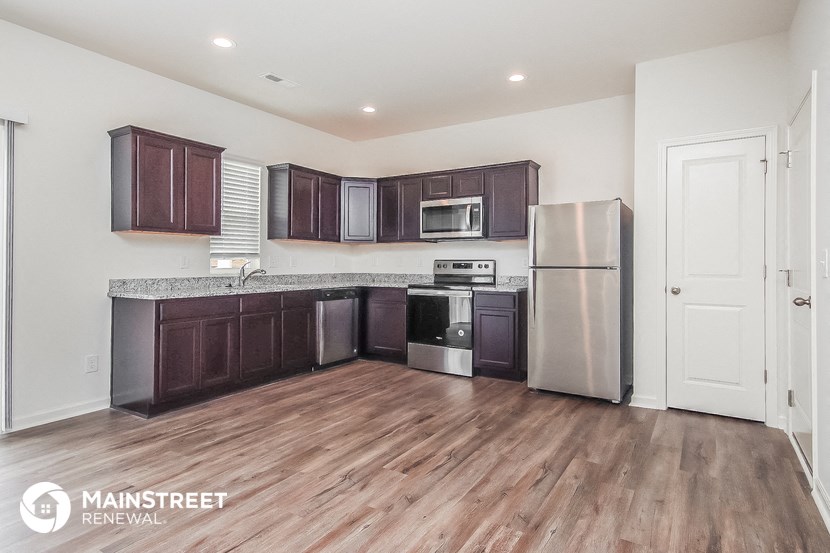a kitchen with dark wood cabinets and stainless steel appliances and a wooden floor