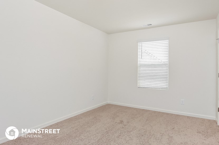 the bedroom of an apartment with a carpeted floor and a window
