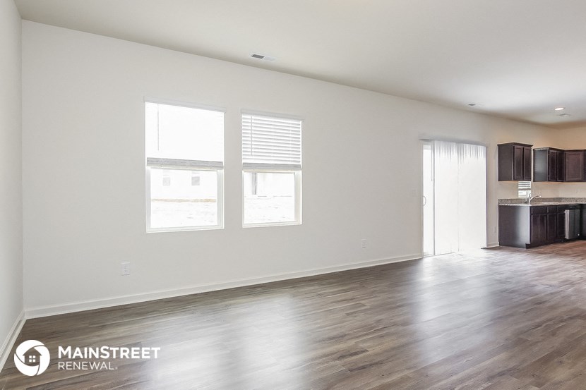 the living room and kitchen of an empty house with wood floors