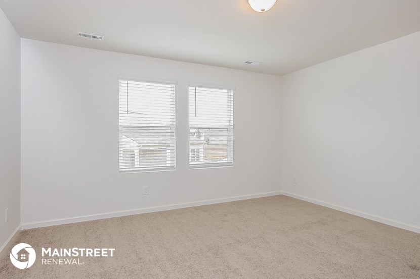 a bedroom with two windows and a carpeted floor