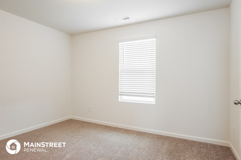 a bedroom with a window and a carpeted floor