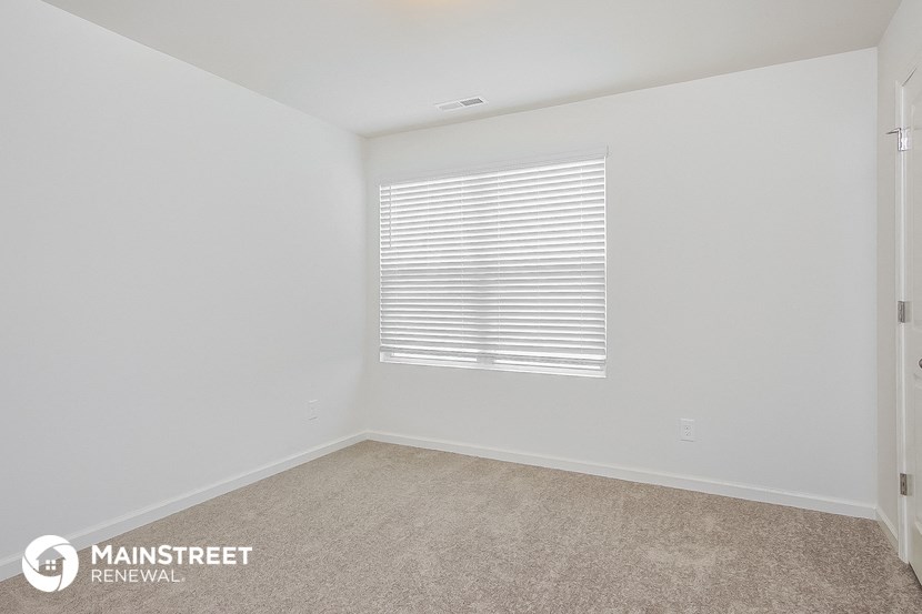 the living room of an apartment with white walls and a window