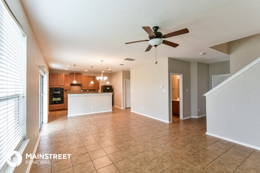 an empty living room and kitchen with a ceiling fan