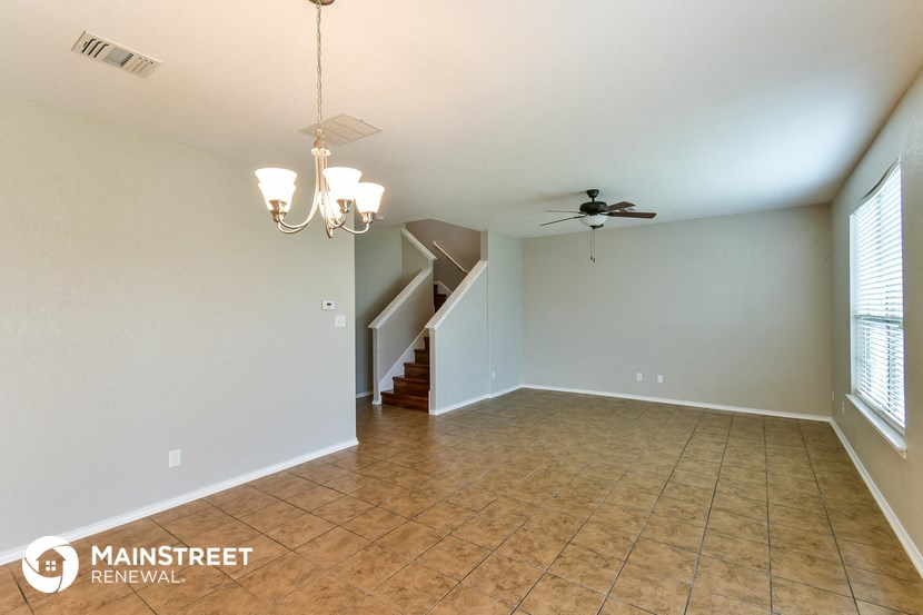 an empty living room with a ceiling fan and a staircase