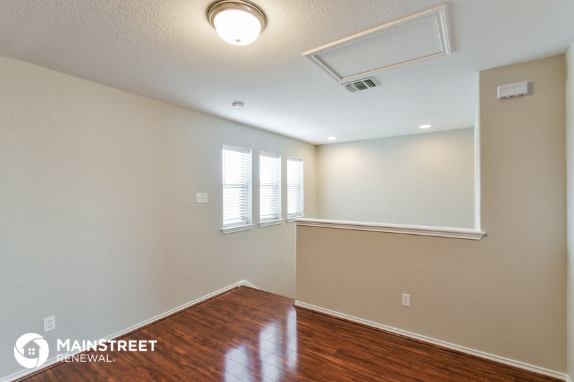 the living room and dining room of an empty home with wood flooring and white