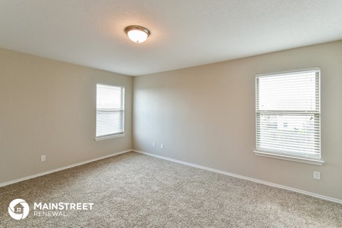 the living room of a home with carpet and two windows