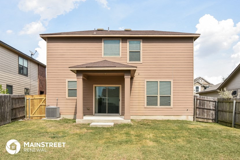 the front of a house with a yard and a wooden fence