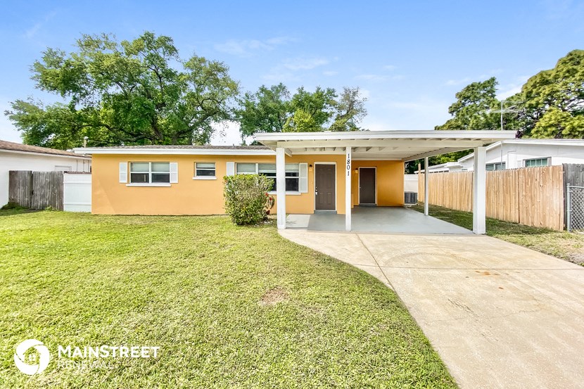 a small yellow house with a yard and a driveway