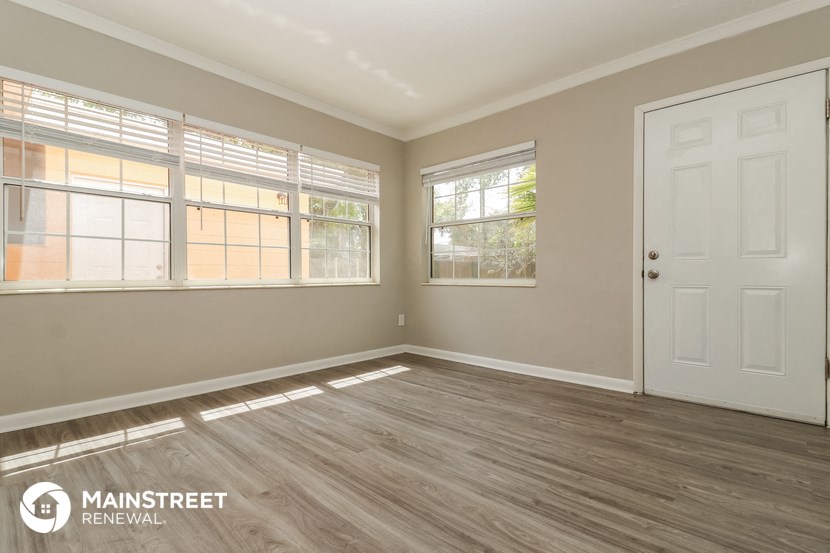 the living room of a home with wood floors and a white door