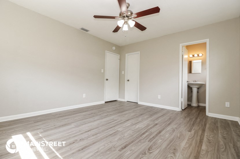 the living room is spacious and has a ceiling fan