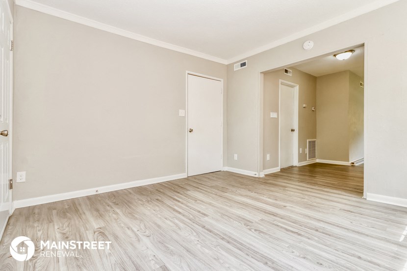 the living room of an apartment with wood floors and white walls
