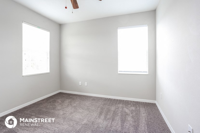 an empty room with carpet and two windows