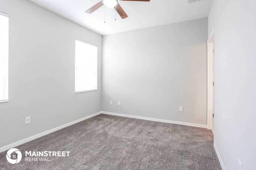 the spacious living room with carpeting and a ceiling fan