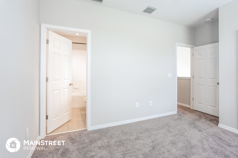 a bedroom with a door to a bathroom and a carpeted floor