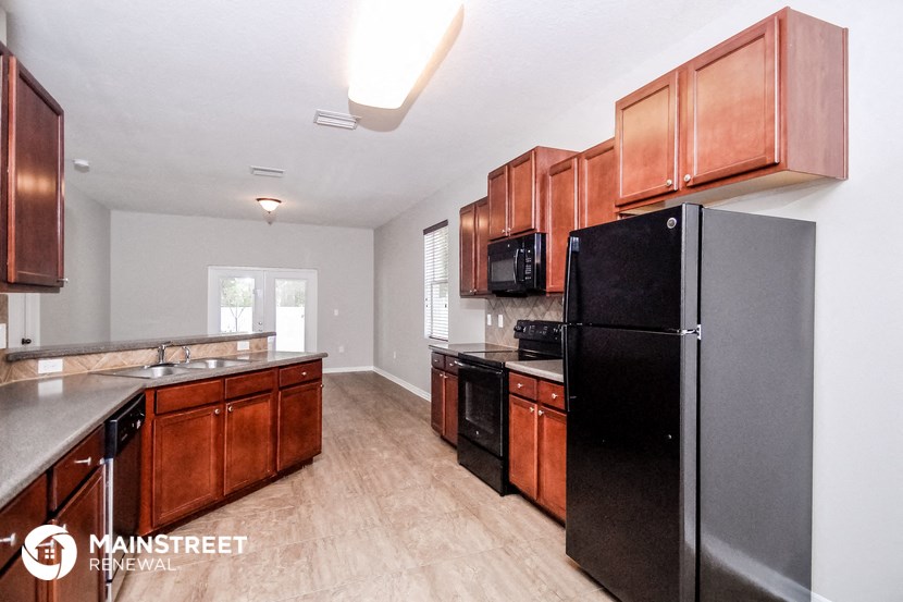 a kitchen with wooden cabinets and a black refrigerator