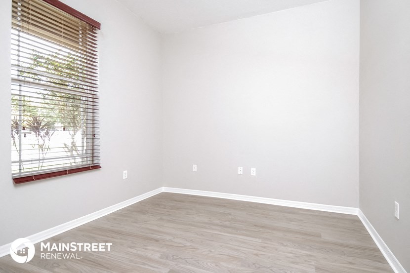 the spacious living room with a large window and wood flooring