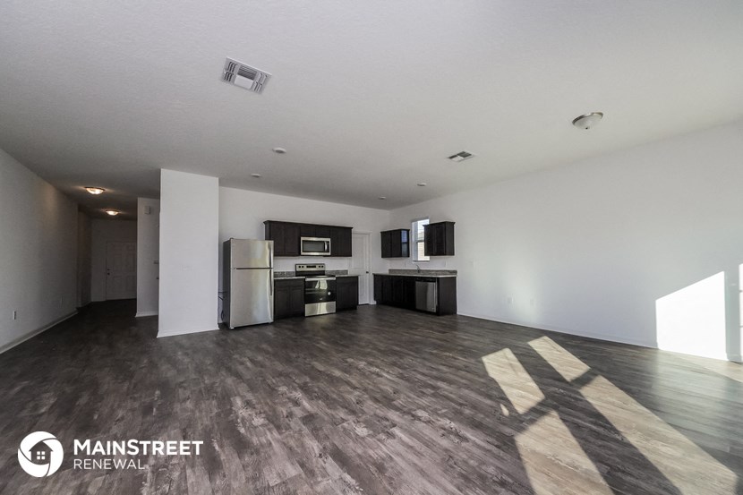 an open living room and kitchen with wood floors and white walls