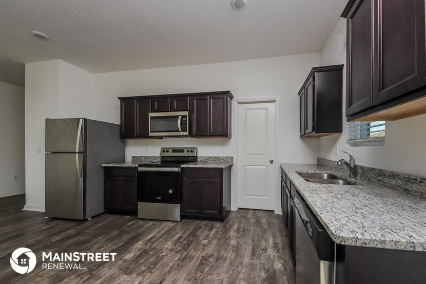 a kitchen with granite countertops and stainless steel appliances and dark wood cabinets