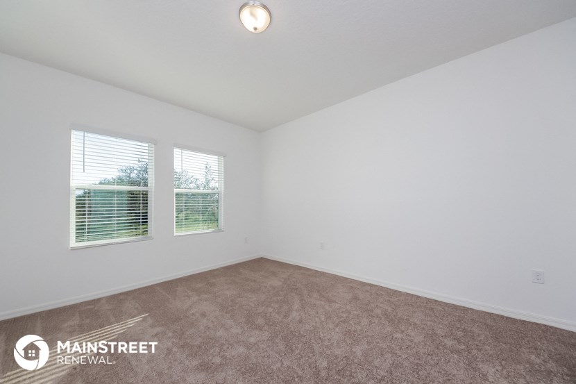 an empty living room with two windows and a carpet