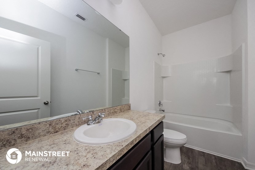 a bathroom with a sink and a toilet next to a tub and a mirror