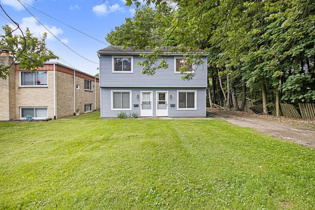 a blue and white house with a yard and a brick house