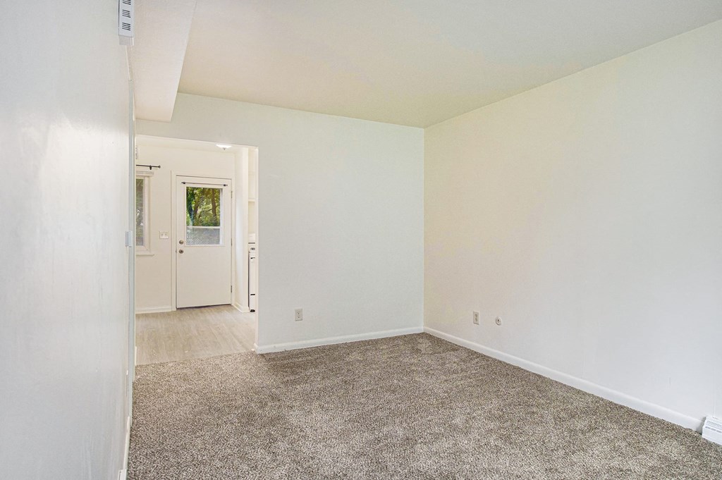 an empty living room with carpet and white walls