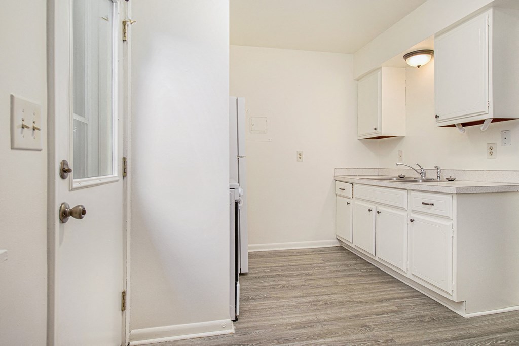 an empty kitchen with white cabinets and a refrigerator