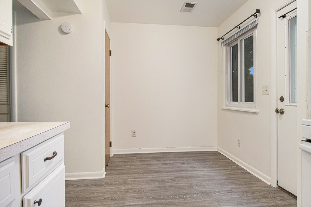 an empty kitchen with white cabinets and a window