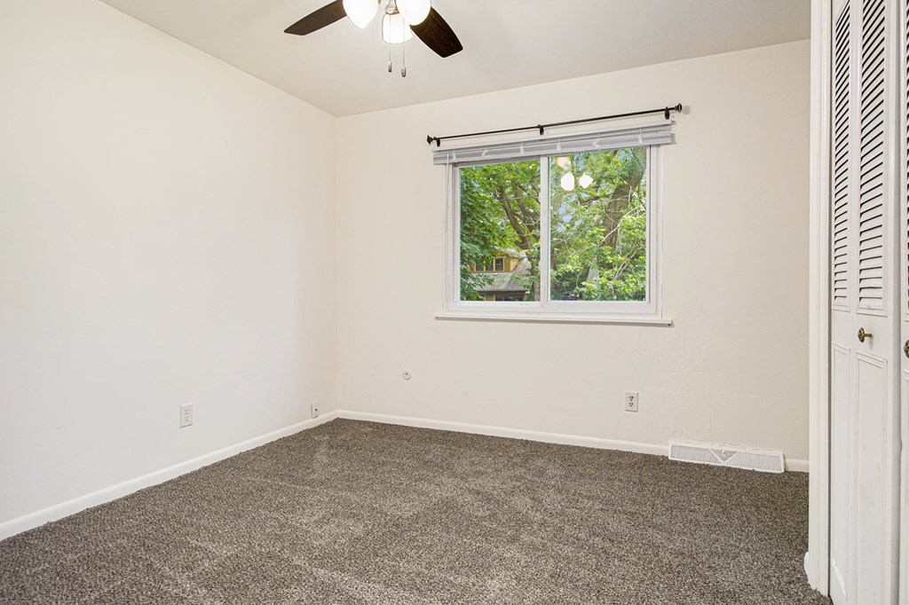 a room with carpet and a window and a ceiling fan