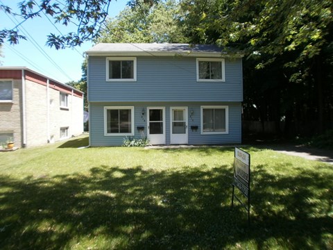 a blue house with a yard and a sign in front of it