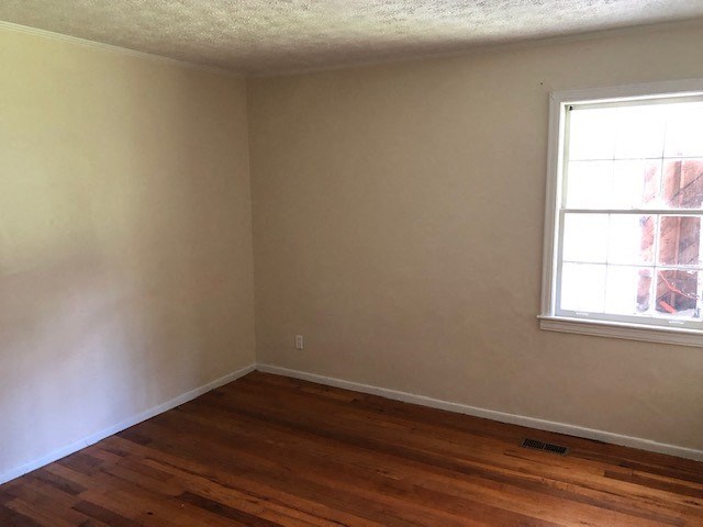 an empty room with a window and wooden floors