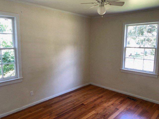 an empty room with a wooden floor and two windows