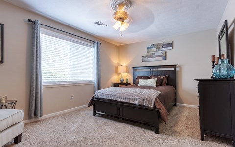 A bedroom with a bed, dresser, and window.