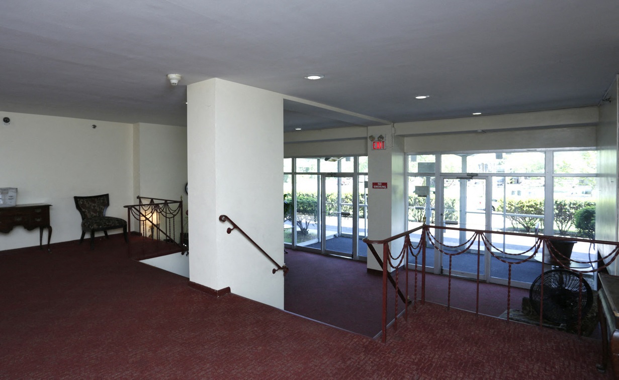 A large room with a red carpet and a staircase.