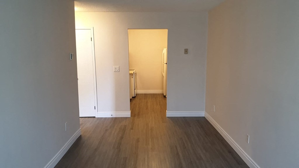 an empty living room with wood floors and white walls